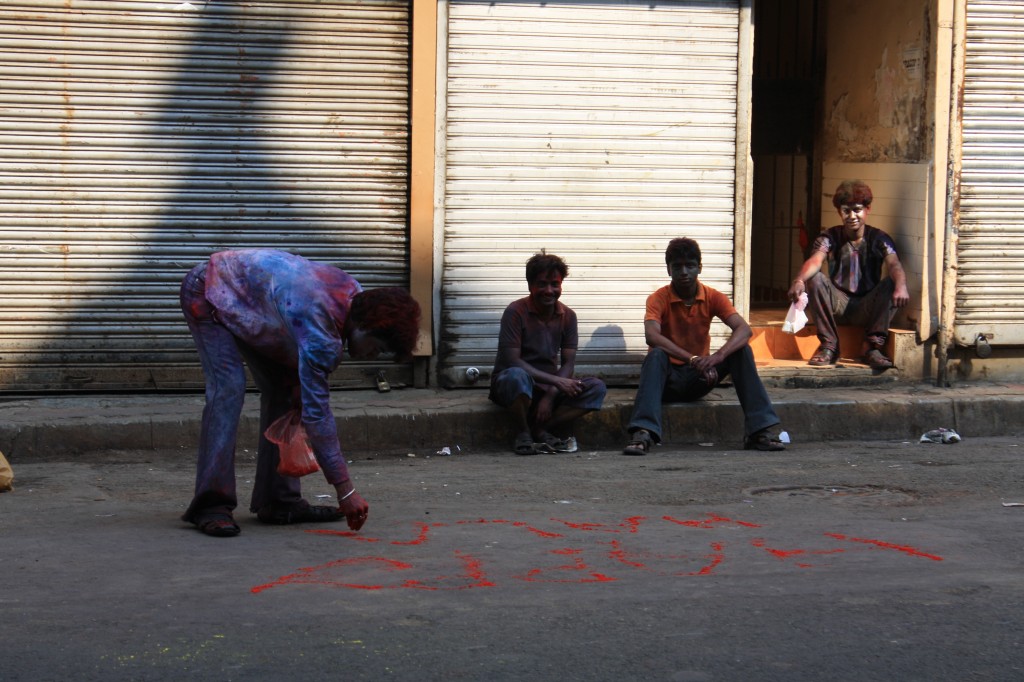 Boy draws Happy Holi on the street