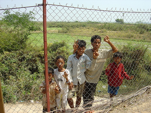 Curious Cambodian children eye peak through the fences of The Killing Fields